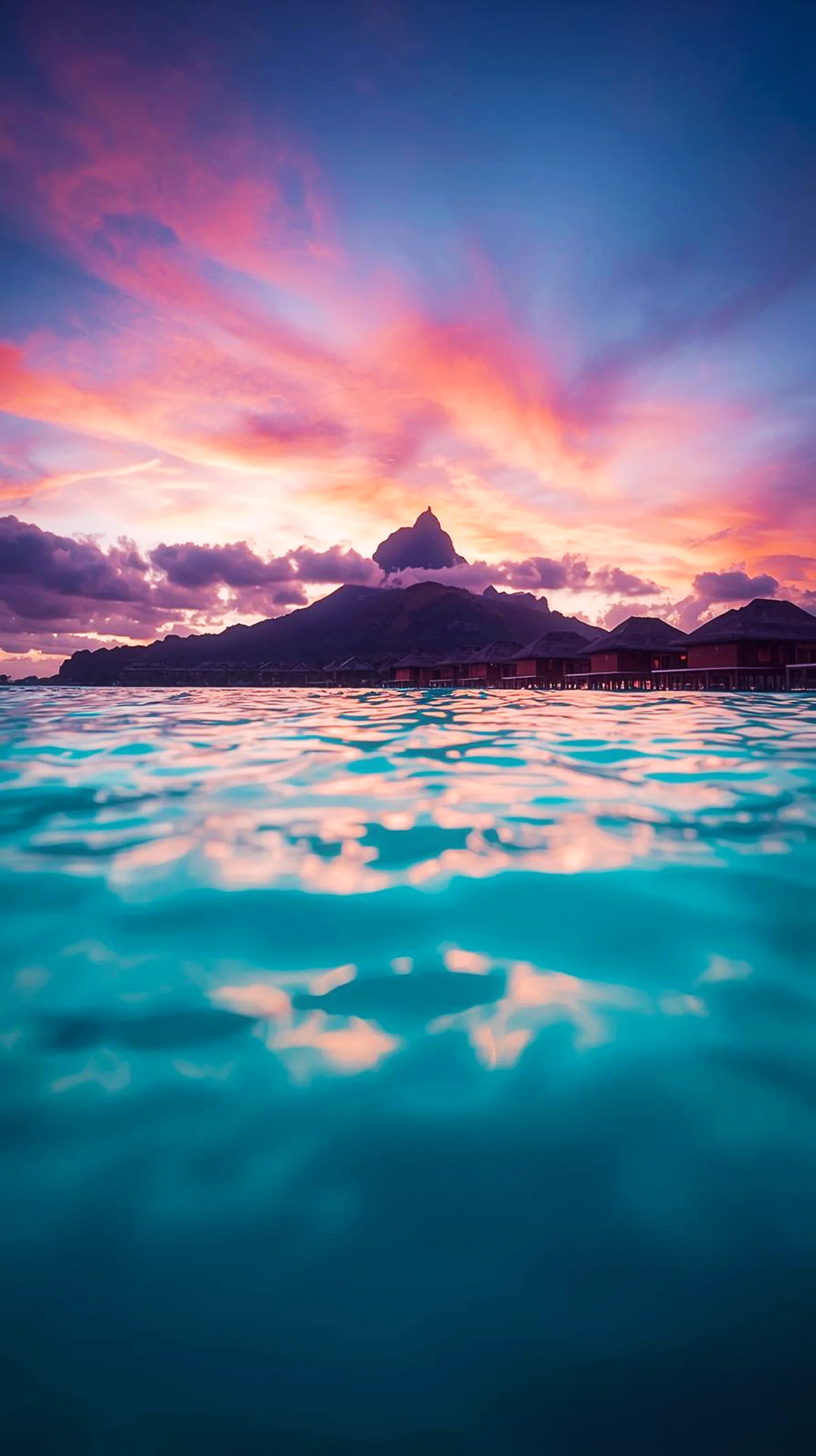 A beautiful tropical sunset over the ocean with mountain silhouettes for mobile wallpaper.