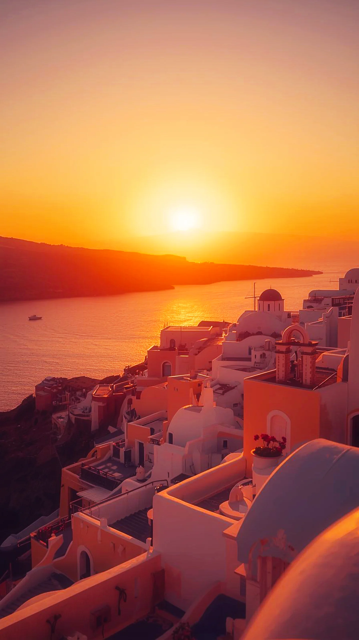 A stunning 4K mobile wallpaper of a golden sunset over the white buildings of Santorini, Greece.