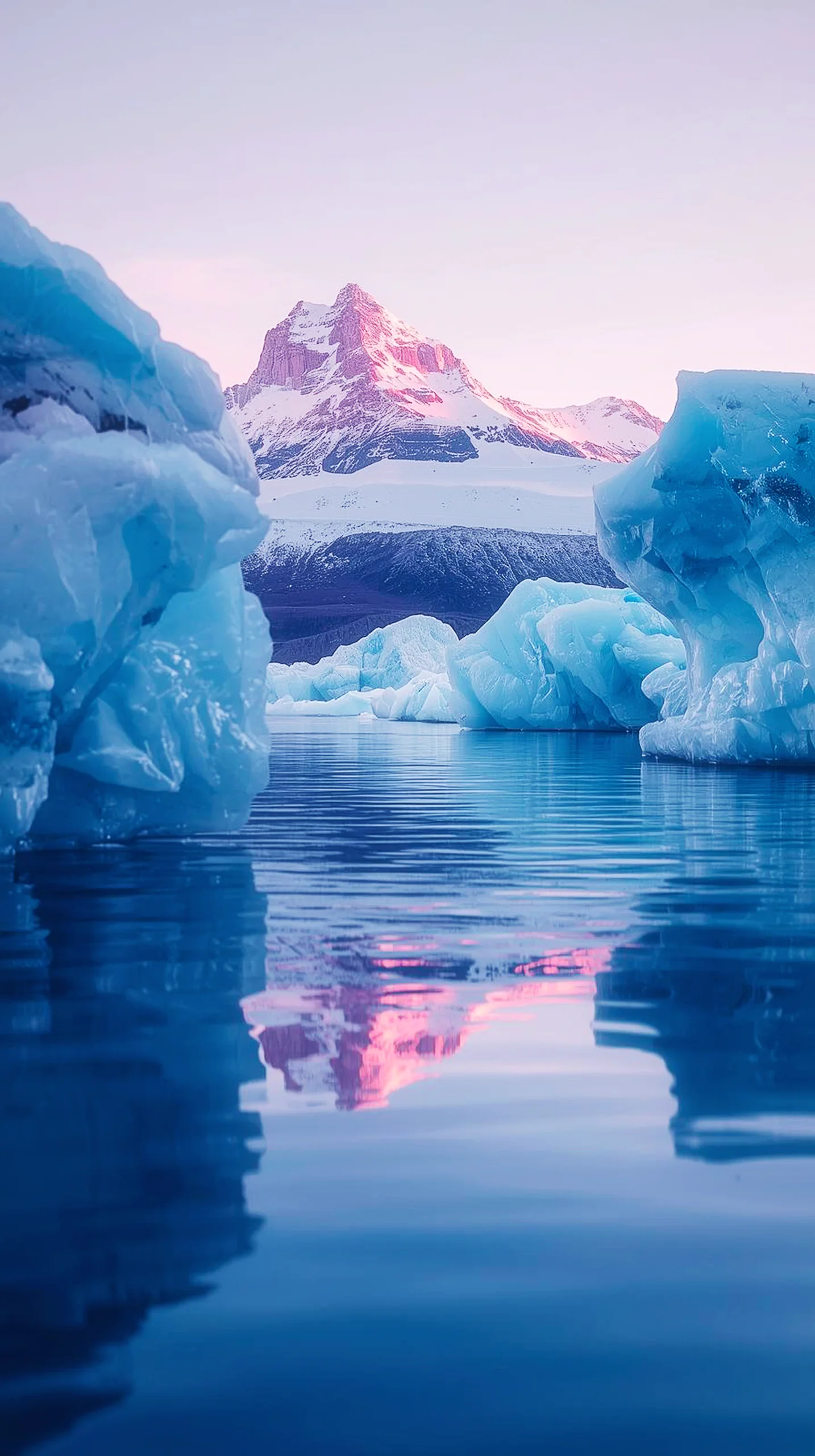 A stunning glacier mountain landscape with blue icebergs reflecting in calm water under a pink sunset sky.