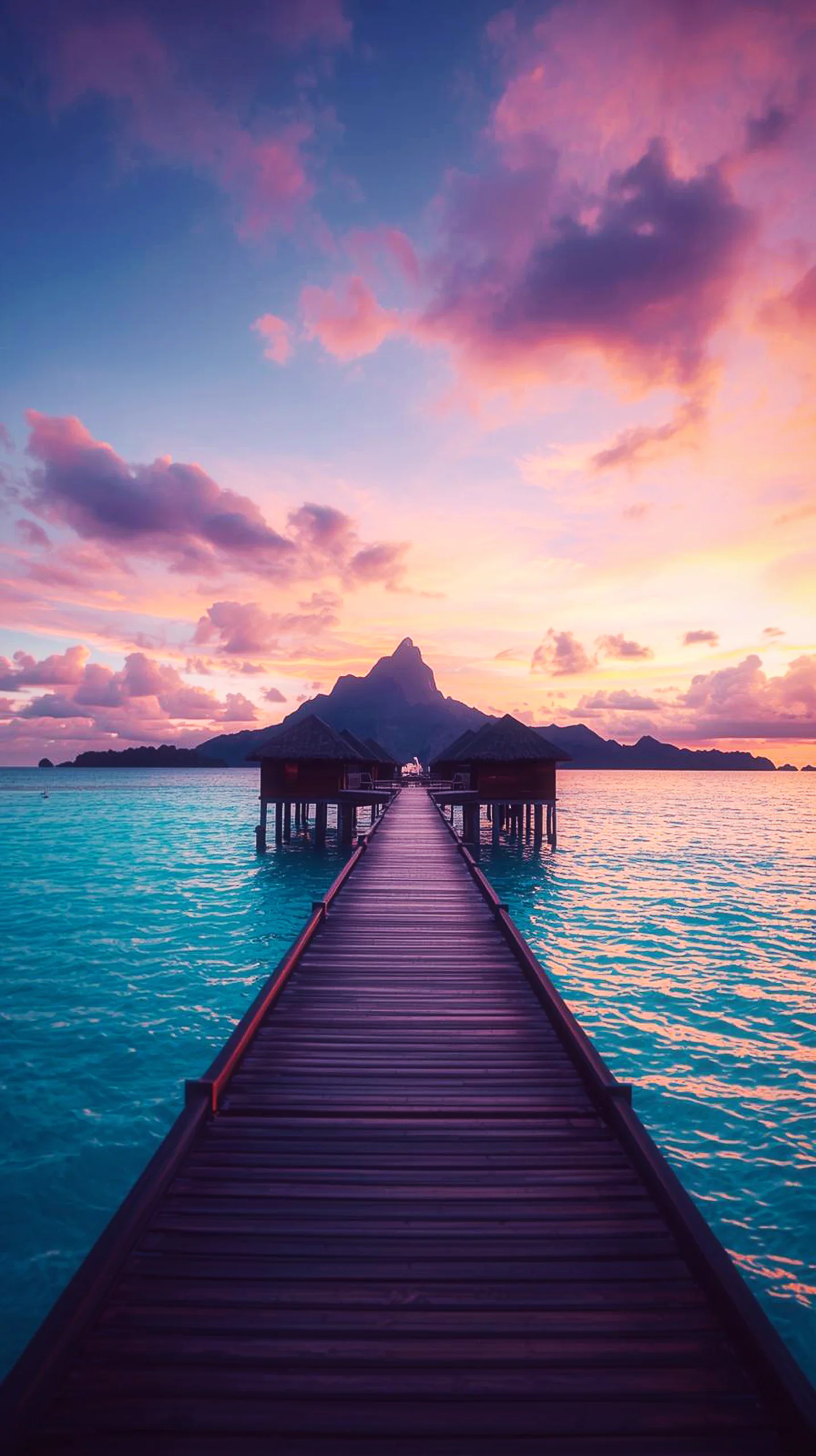 A wooden pier leading to a mountain island during a vibrant purple sunset over turquoise water.